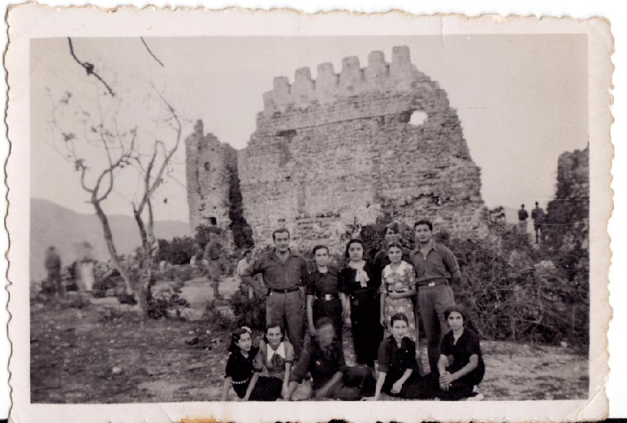 La imatge mostra un grup de soldats i de xiques del poble poc després de l’entrada de l’exèrcit nacional en Artana. Com es sap, la 4ª Divisió de Navarra va entrar a Artana pel Castell el 4 de juliol de 1938, i va causar un gran entusiasme en part de la població. Fruit d’aquest entusiasme fou l’amistat entre alguns soldats i famílies del poble, que es van prolongar durant anys després de la guerra. En la fotografia s’hi reconeixen les xiques del poble: d’esquerra a dreta i de dalt avall, Felicidad de Coloma, Doloretes de Clàudia, Genoveva, Lolita el Rosso, Marí Roqueta, Doloretes de Roqueta i Marí Racó (la primera i la penúltima vestides de falangistes). Quant als soldats, algunes de les xiques presents n’identifiquen dos: el primer per l’esquerra era intendent i l’anomenaven “el Carnisser”. I el de més a la dreta es deia Jaime, era un xic de Barcelona que, una vegada acabada la guerra, va tornar a Artana en nombroses ocasions, de vegades acompanyat per sa mare. Foto cedida per Marí Racó.