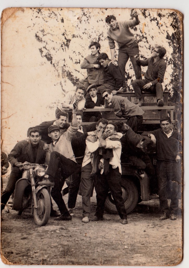 Una colla d'amics de festa. A la furgona de darrere hi ha una pianola, així que pot ser una festa de Quintos. Sobre la pianola, José Pansa, Josep Baleso, Vicente Vilara i un desconegut. Immediatament baix, Miguel de Panxut, Juanito Calo (amb gorra) i Benjamín de Cabedo. Més avall encara, Vicente Escaleta, Bastero, Pepe Solo, Cantos i Juanito Corina. Sobre la moto, Joaquín de Músic i a la vora, amb gorra, un desconegut.